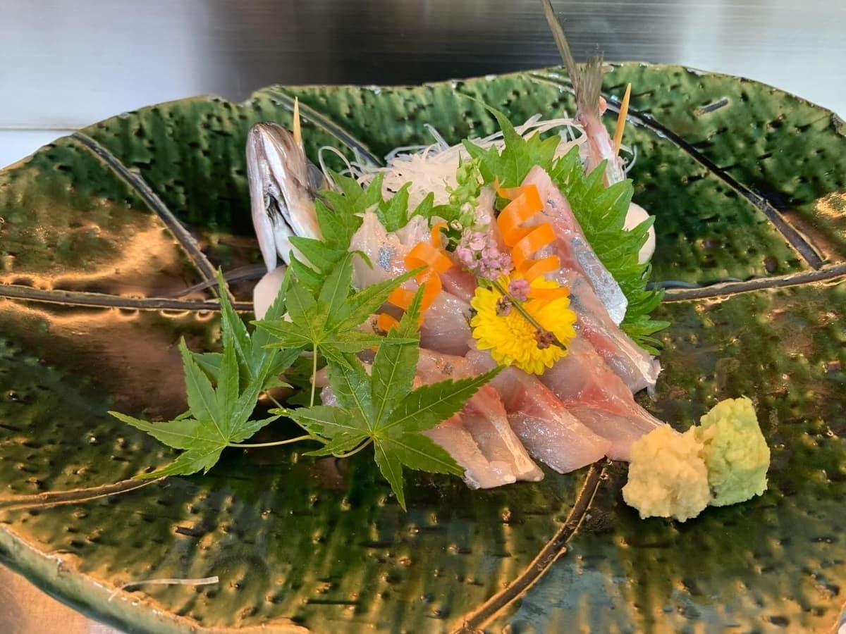 大皿に紅葉や花を添えて盛り付けた新鮮な魚の刺身