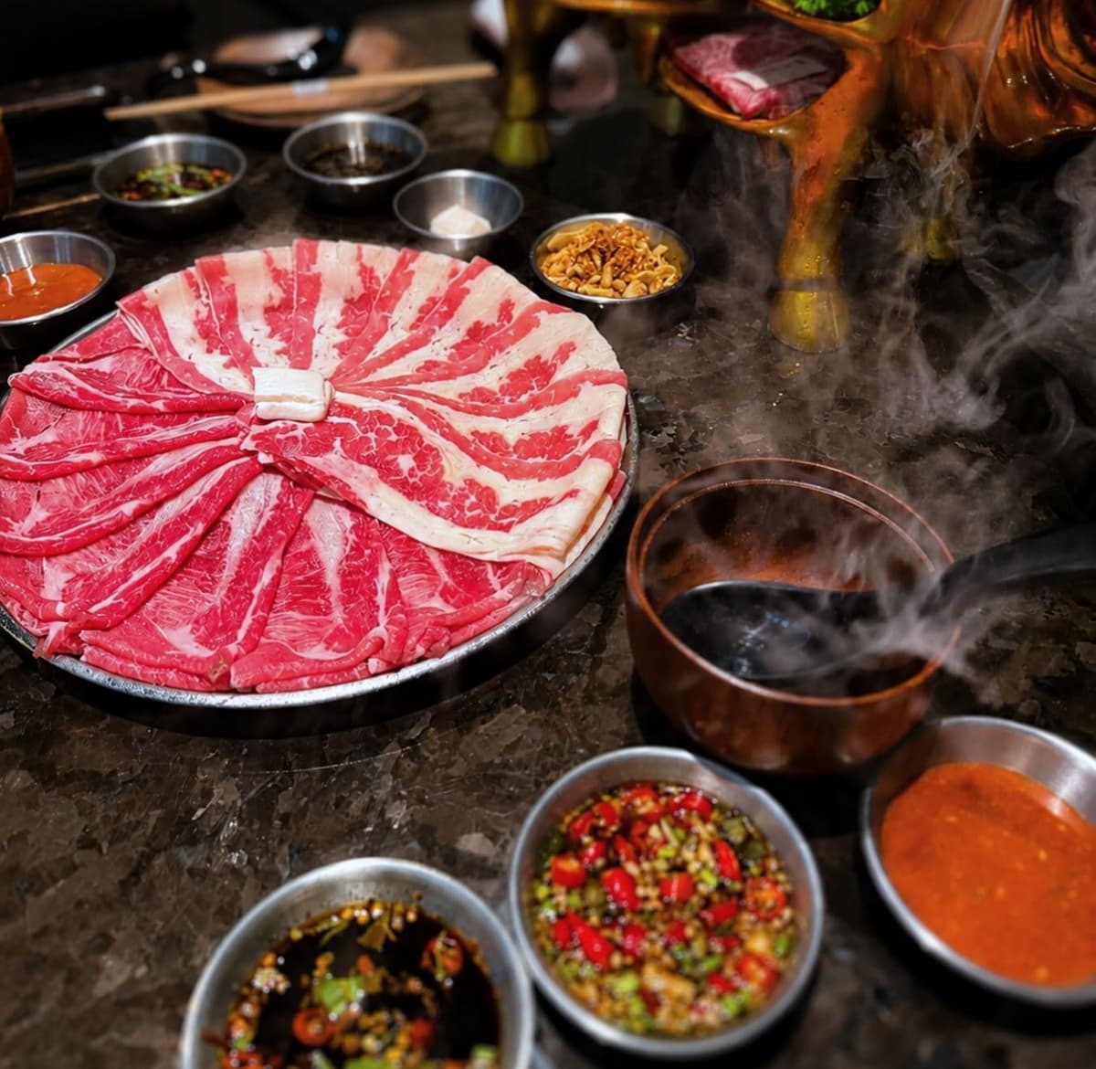 薄切り肉の大皿と複数のタレが並ぶYuzu Yakinikuの焼肉テーブル