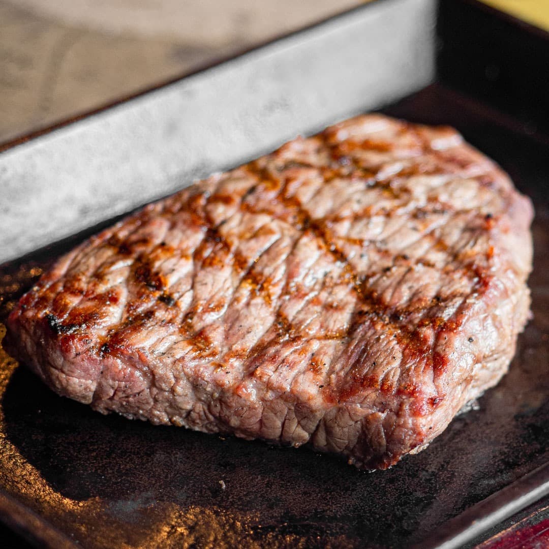 熱々の鉄板の上で肉汁をたたえながらジューシーに焼き上げられた、厚切りのビーフステーキ。