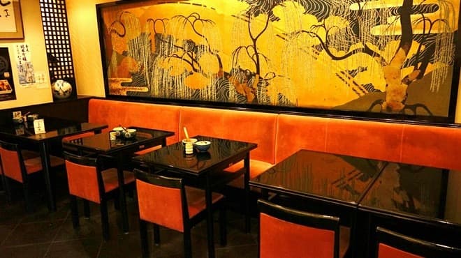 オレンジ色の椅子と和風の壁画が印象的なEndo Sushiの店内席