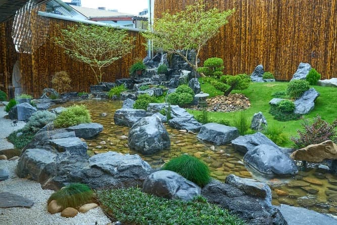 滝や池、岩、植栽が美しく配置されたSushi Juban Takumi Ekkamaiの日本庭園