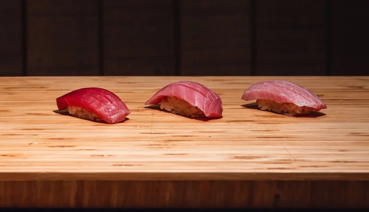 木製の寿司カウンターに並べられたマグロの握り寿司3貫