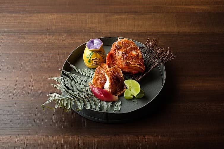 木製テーブルに盛り付けられた焼き魚とスダチ