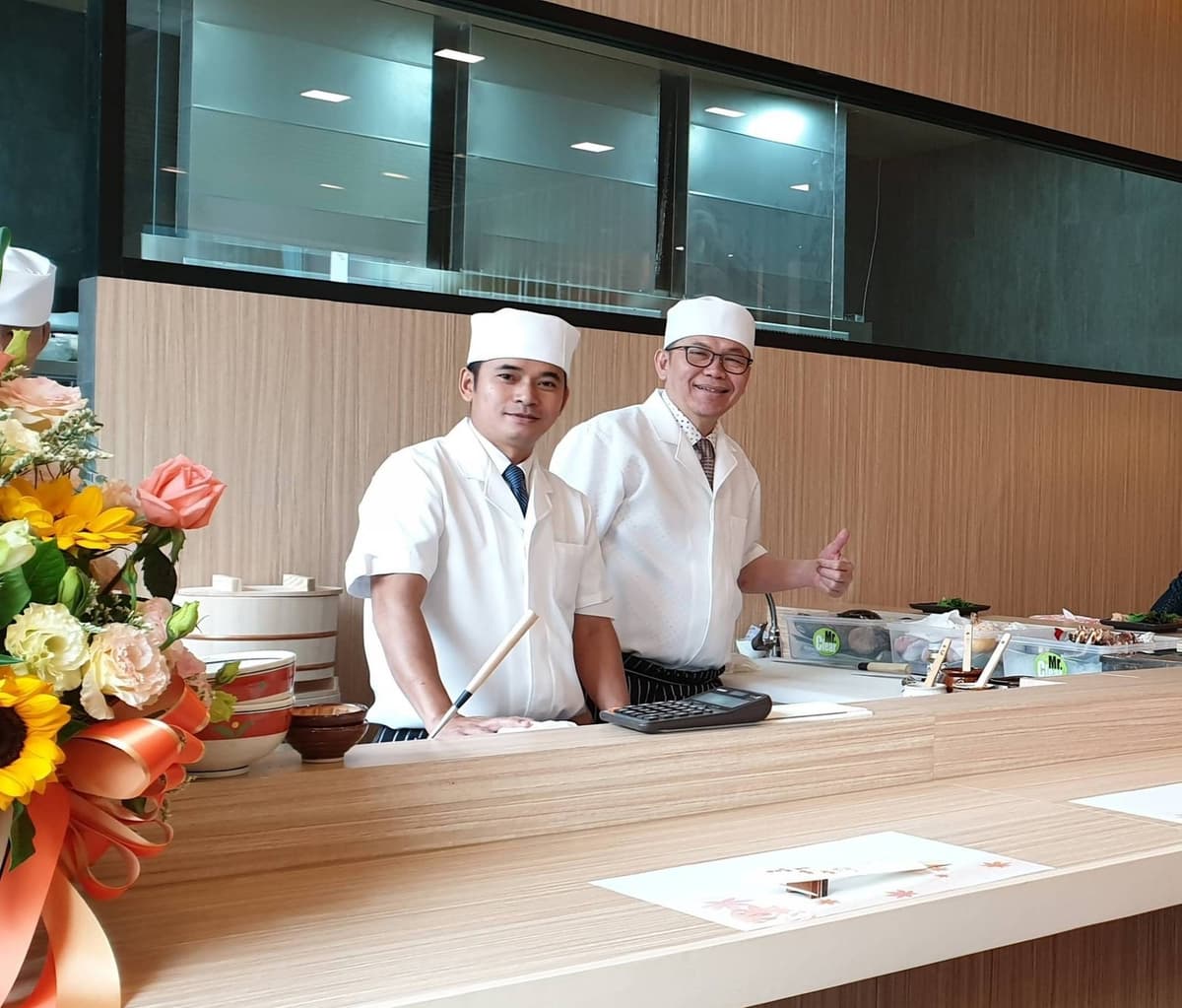Sushi Totoyaの寿司カウンターに立つ白衣姿の寿司職人