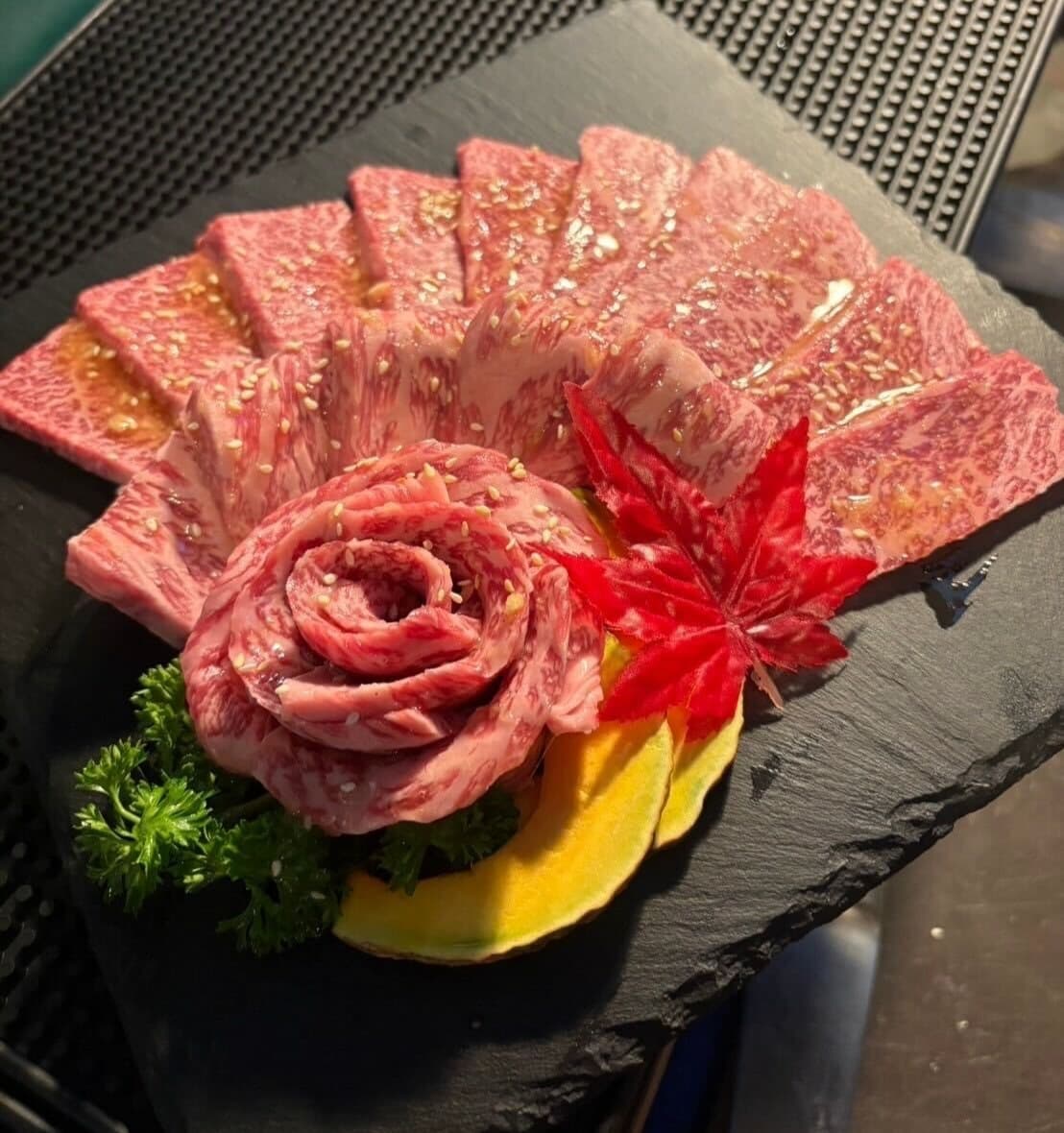 黒いプレートに美しく盛り付けられた霜降り牛肉の焼肉盛り合わせ