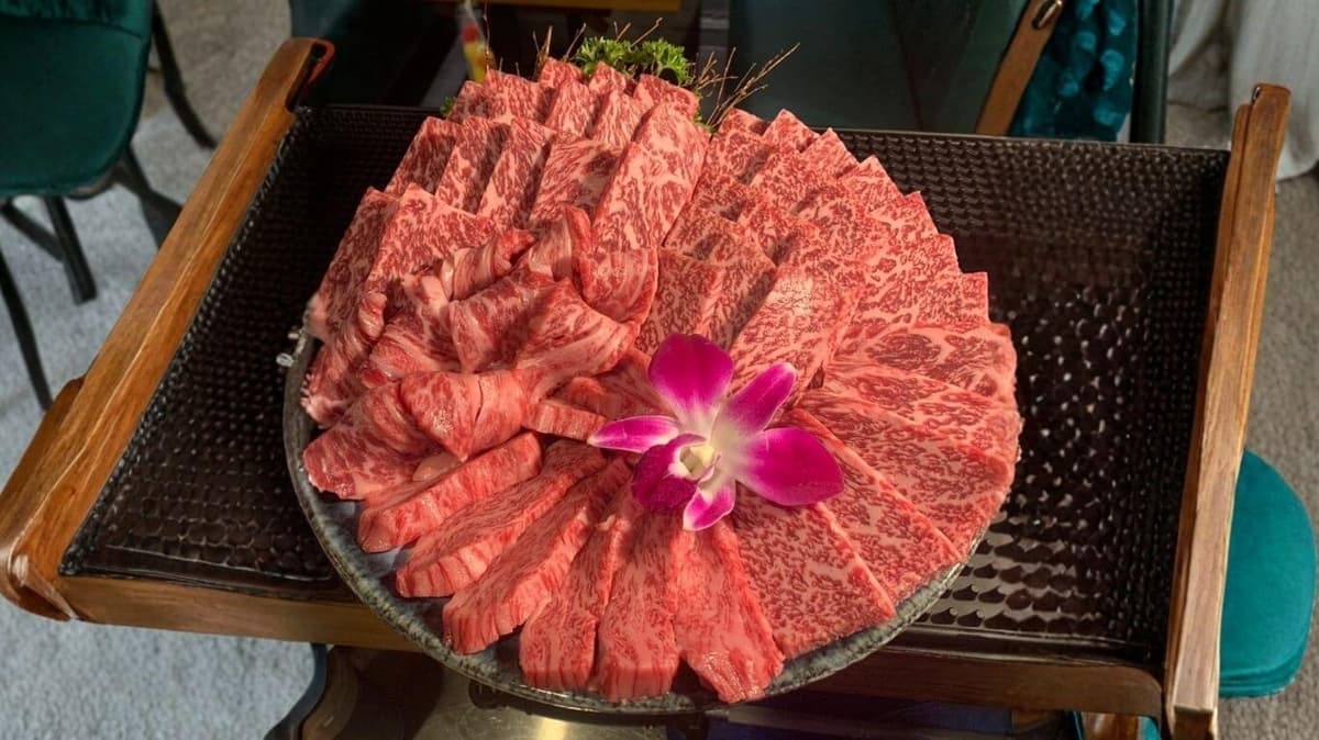 花を添えた大皿に並ぶ霜降り牛肉の焼肉盛り合わせ