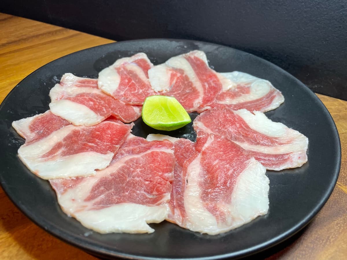 ライムを添えて円形に盛り付けた脂身の多い焼肉用牛肉