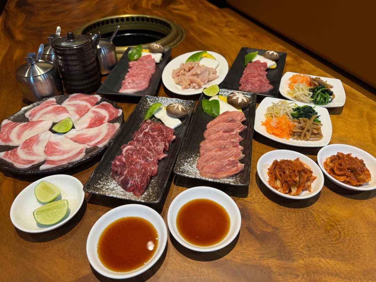 数種類の焼肉用肉、焼き野菜、ナムル、キムチが並ぶテーブル