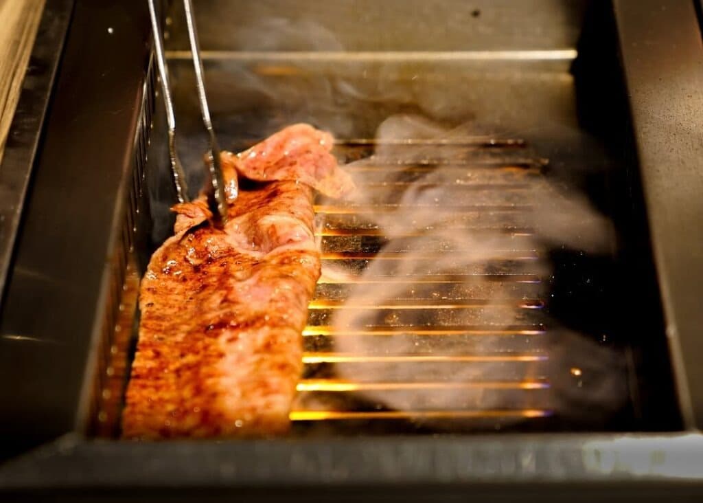 焼き網の上で薄切りの和牛を香ばしく焼く様子