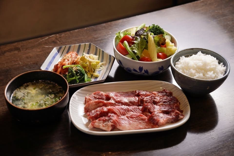 木製テーブルの上に並べられた、焼肉定食の一例。