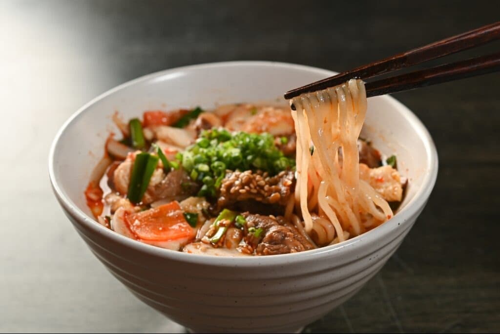 牛肉入りの辛い麺料理を箸で持ち上げたクローズアップ写真