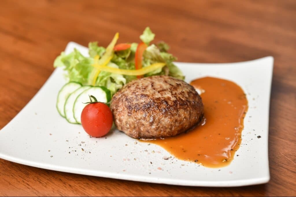 ワギューハンバーグにソースとサラダを添えた一皿