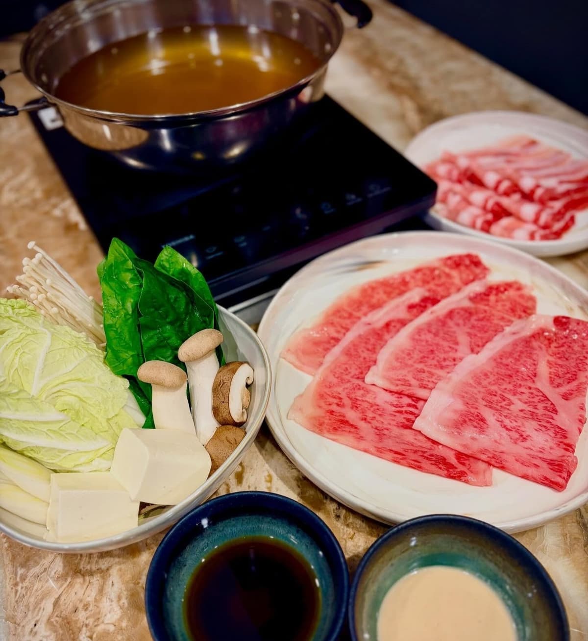 しゃぶしゃぶ用の牛肉と野菜、鍋、つけだれを並べたセット