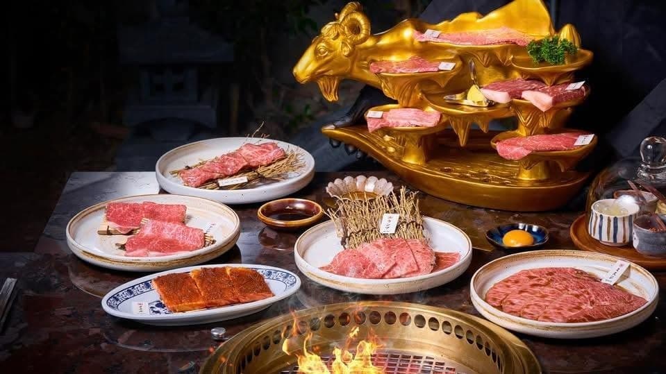 金色の牛型プレートに盛られた焼肉用の肉と、卓上ロースターを囲むYuzu Yakinikuの料理
