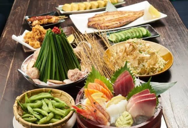 「なぎ屋アソーク店」名物の、ボリューム満点なもつ鍋と刺身盛り合わせ