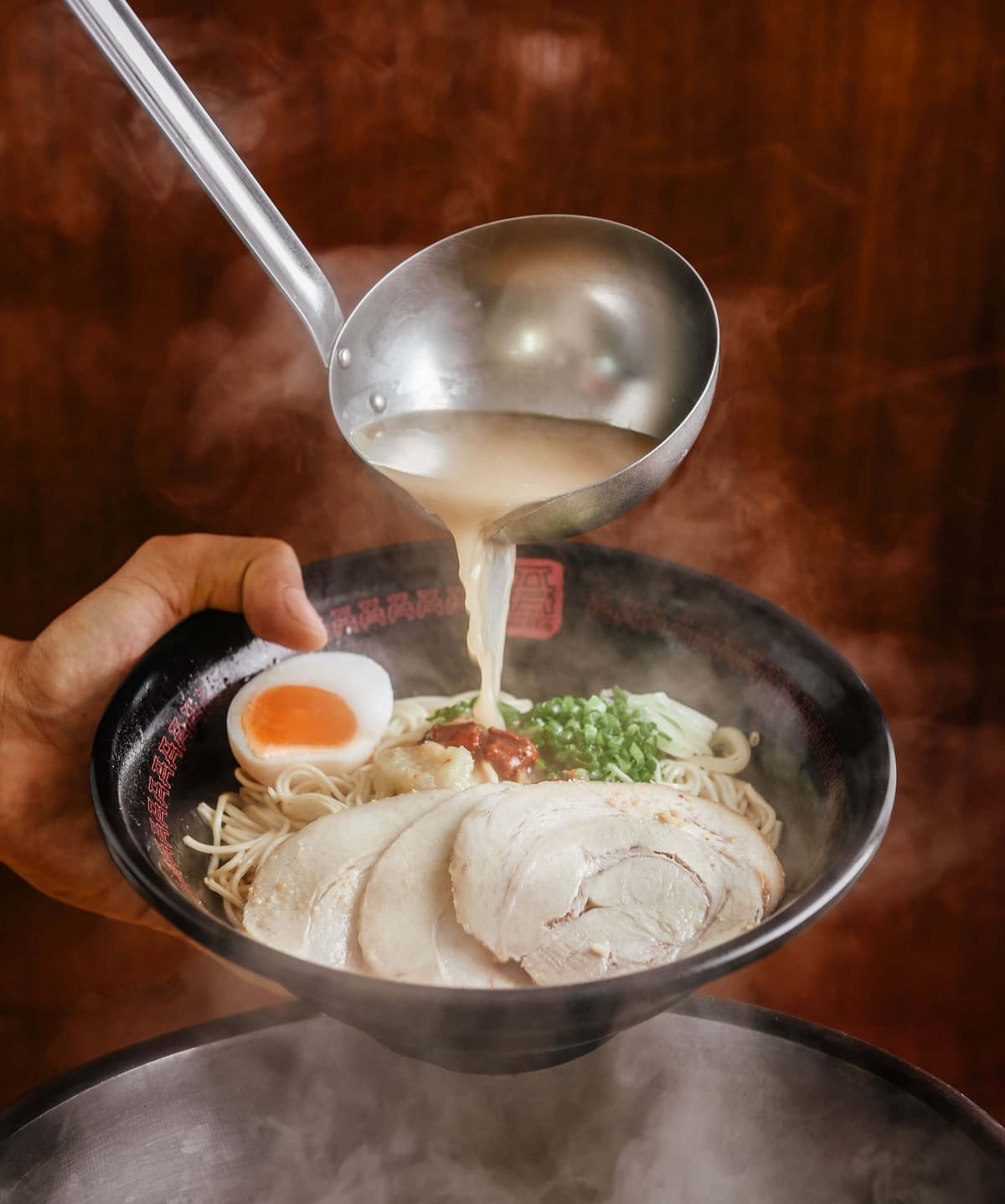 A RAMENの豚骨スープを注ぐラーメンの仕上げシーン