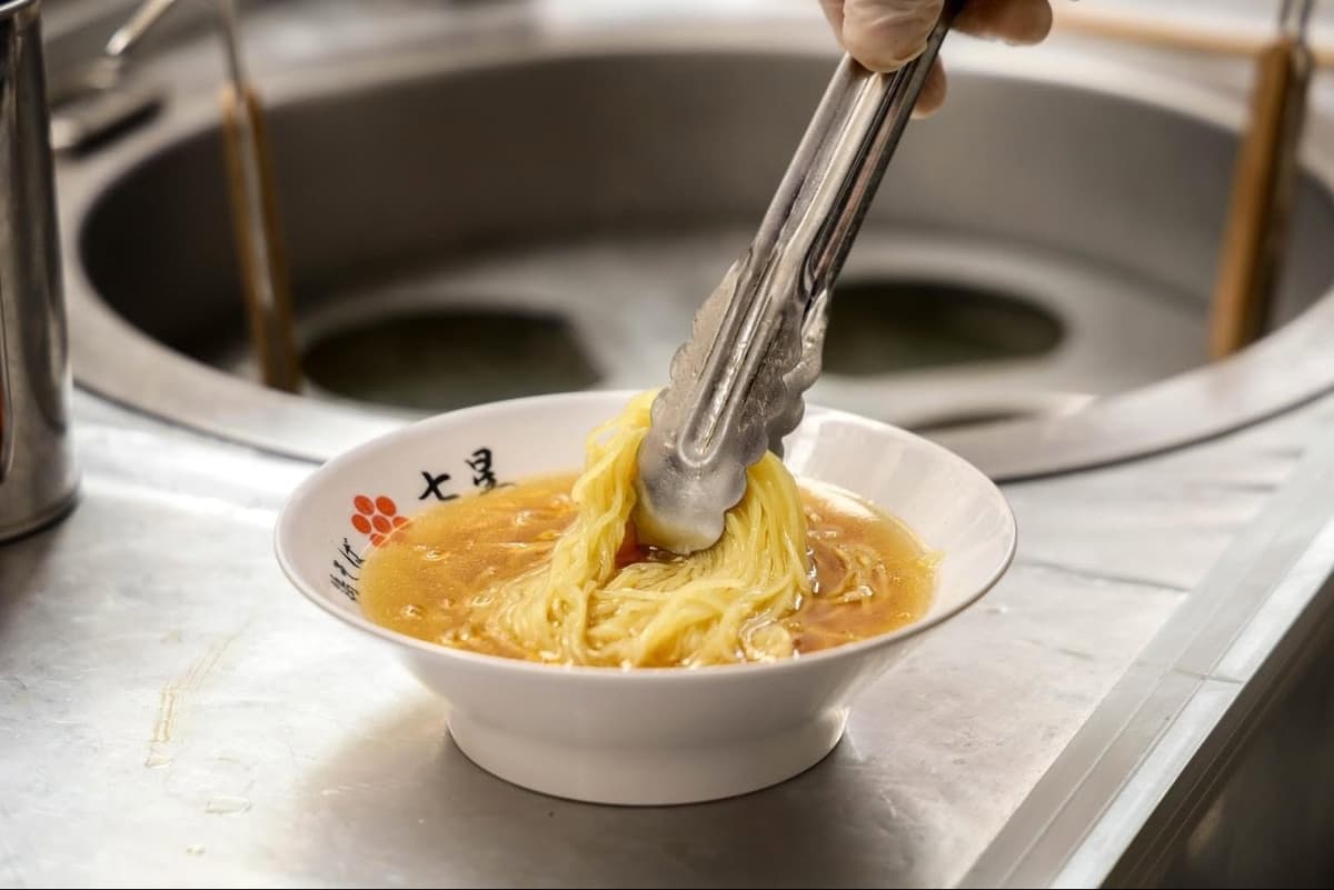 七星ラーメンで鶏白湯スープに細麺を入れる調理風景