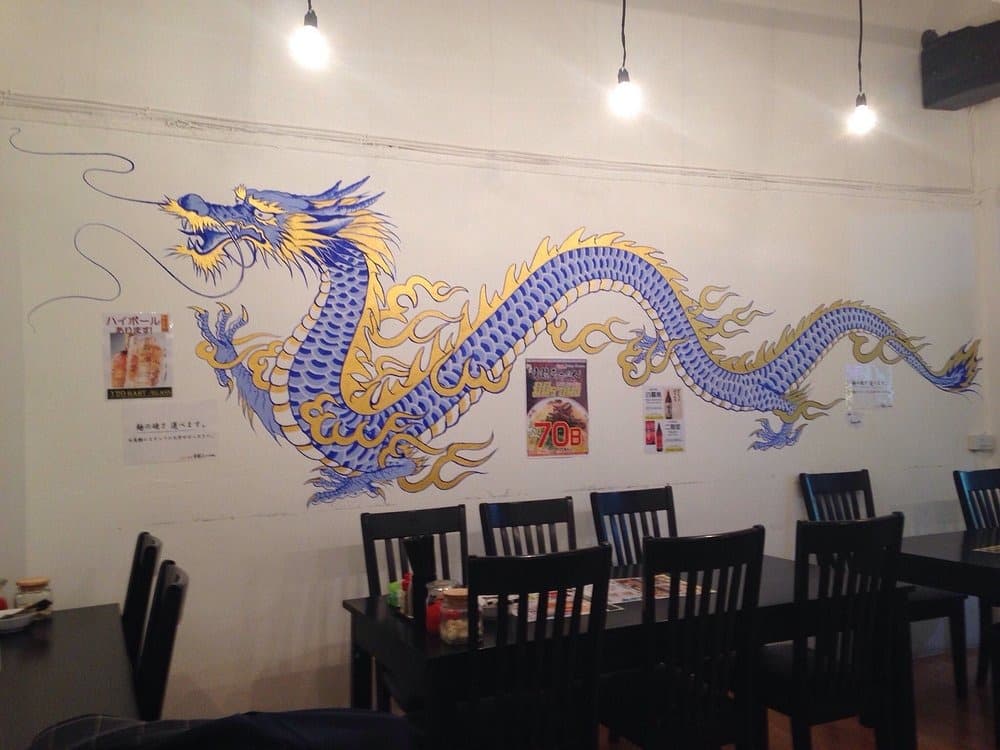 青龍ラーメン店内の龍が描かれた壁画とテーブル席