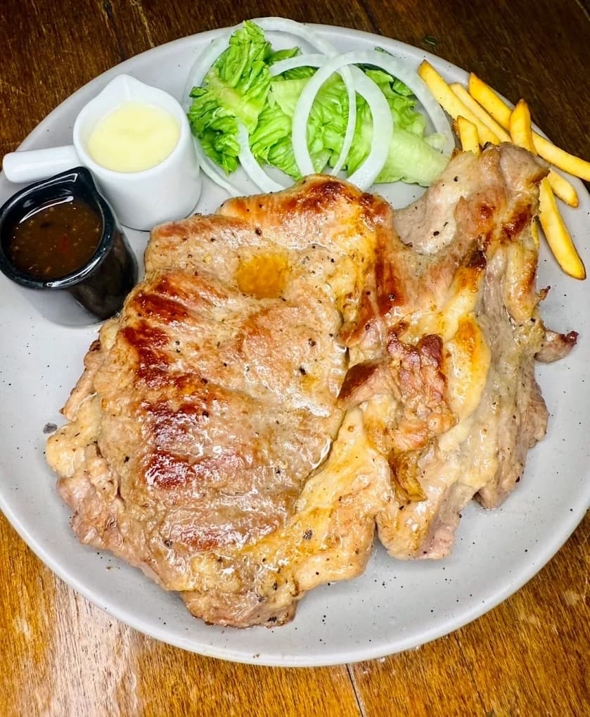 白いお皿に盛られた大きな豚肉のステーキ(グリル)。
