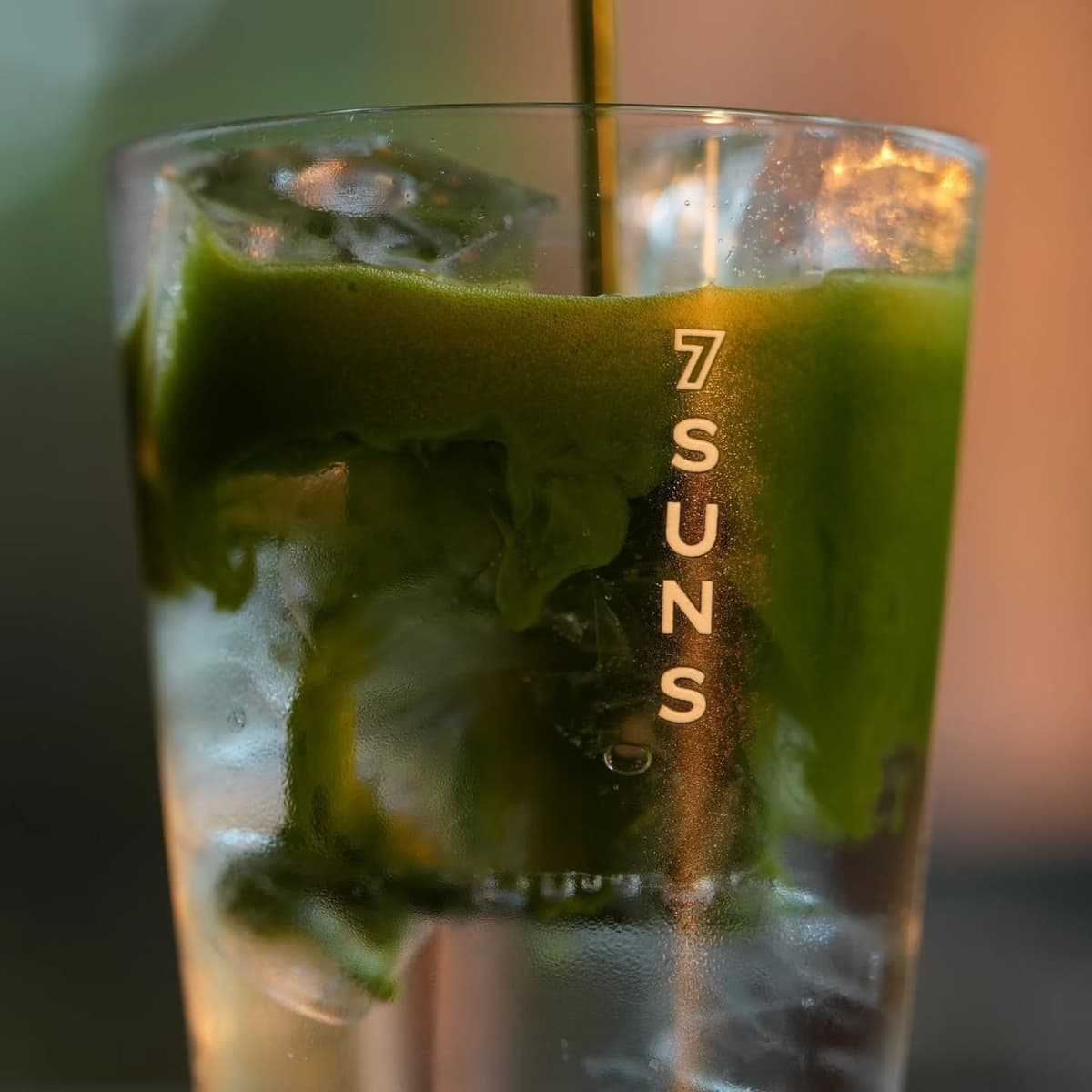 7SUNSのロゴ入りグラスで提供される氷入りの濃厚な抹茶ドリンク