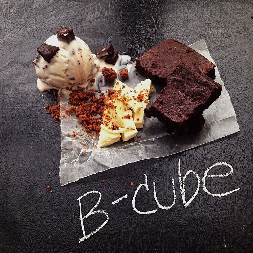 「B-cube」と書かれた黒いテーブルにアイスクリームとチョコレートブラウニーを盛り付けたデザート