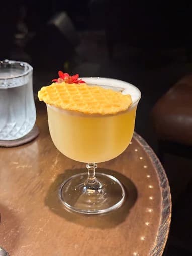 008 Barのシグネチャーカクテル、ワッフル状の飾りと赤い花を添えた一杯
