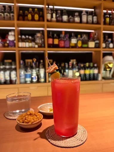 Lost in Thaislationのバーカウンターで提供される赤いカクテル
