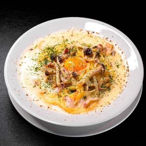 ベーコンときのこ、卵黄をのせたThonglor Rumbaのクリーム系パスタ