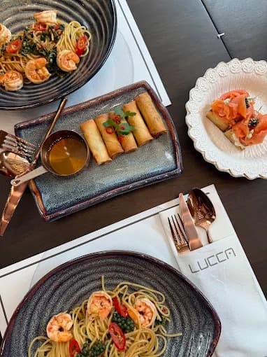 Lucca Thonglorのエビのパスタや春巻き、サーモン料理が並ぶテーブル