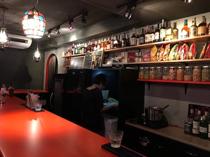 Zola Snack Barの赤いカウンターと酒類が並ぶ店内風景