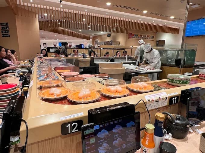 Katsu Midori Sushiの回転寿司レーンと職人が寿司を調理する店内風景